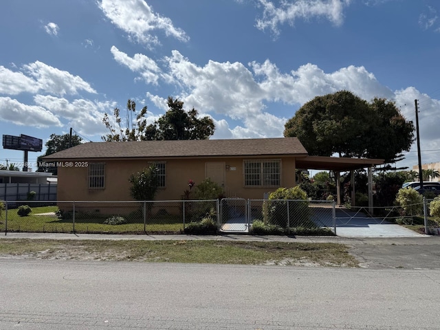 view of front of house with a carport, a fenced front yard, concrete driveway, and stucco siding