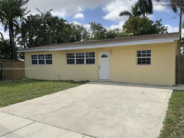 single story home featuring driveway, a front yard, fence, and stucco siding