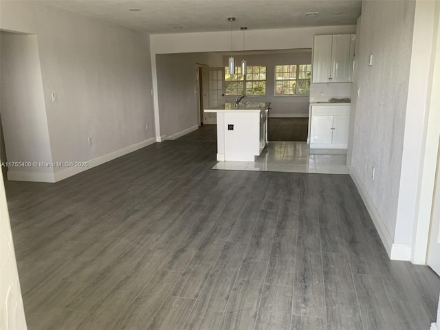 interior space featuring baseboards, dark wood-style floors, and white cabinetry