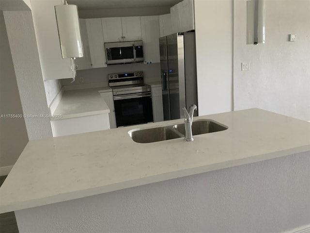 kitchen featuring light countertops, white cabinets, stainless steel appliances, and a sink