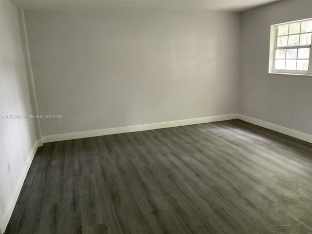 empty room featuring dark wood-type flooring and baseboards