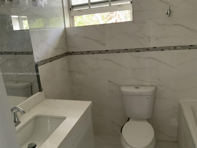bathroom with tile walls, a bath, vanity, and toilet