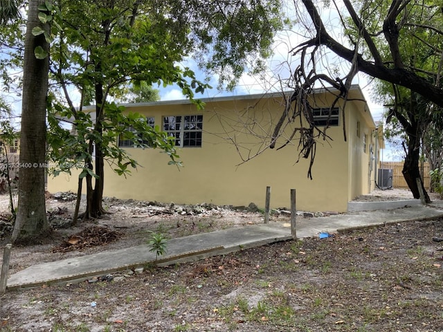 view of home's exterior featuring central air condition unit, stucco siding, and fence