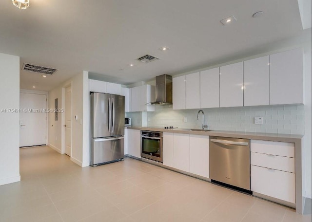 kitchen with a sink, visible vents, appliances with stainless steel finishes, wall chimney range hood, and decorative backsplash