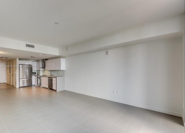 unfurnished living room with tile patterned floors, a sink, visible vents, and baseboards