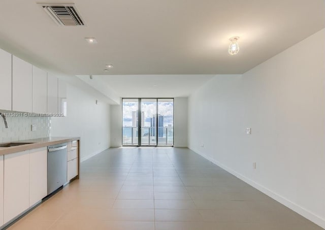 kitchen with tasteful backsplash, visible vents, dishwasher, a wall of windows, and a sink