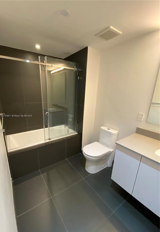 full bathroom featuring toilet, visible vents, vanity, tiled shower / bath, and tile patterned floors