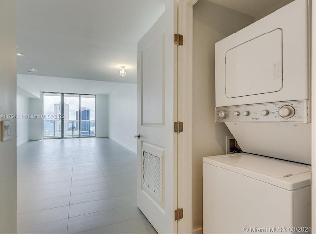 clothes washing area with light tile patterned floors, laundry area, visible vents, and stacked washer / drying machine