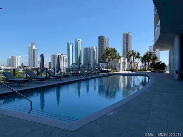 pool with a patio area and a city view