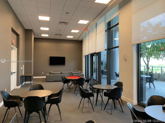 dining space featuring a towering ceiling, baseboards, visible vents, and a drop ceiling