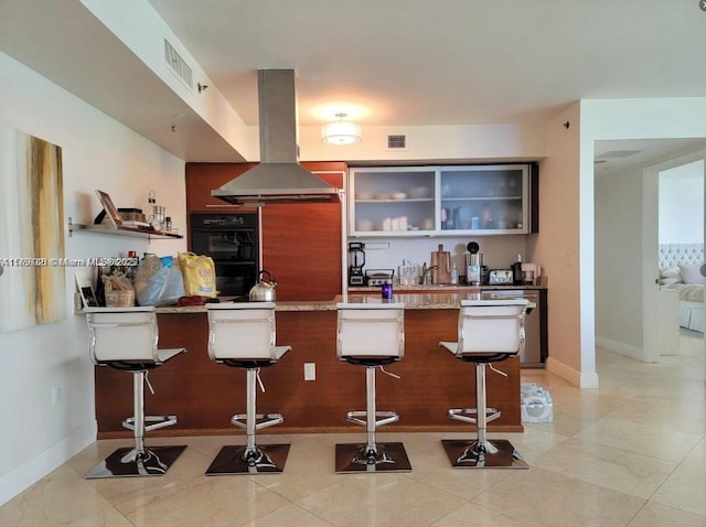 1800 S Ocean Dr Unit 1510, Hallandale Beach, FL 33009 - kitchen featuring island exhaust hood, a kitchen bar, a peninsula, open shelves, and baseboards