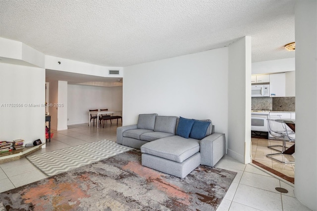 living room with visible vents, light tile patterned floors, and a textured ceiling