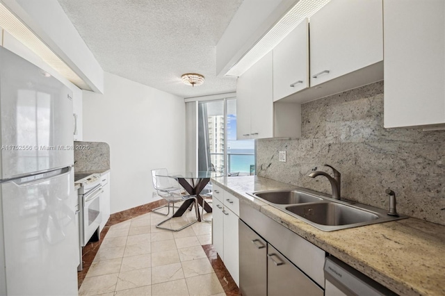 kitchen with decorative backsplash, white cabinets, a sink, a textured ceiling, and white appliances