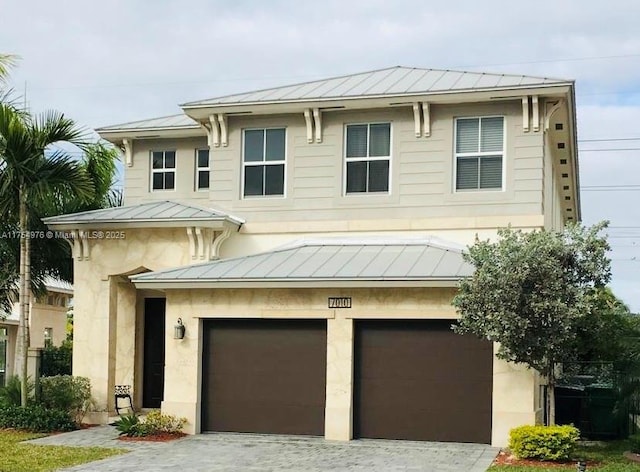 view of front of property with a garage, a standing seam roof, driveway, and metal roof