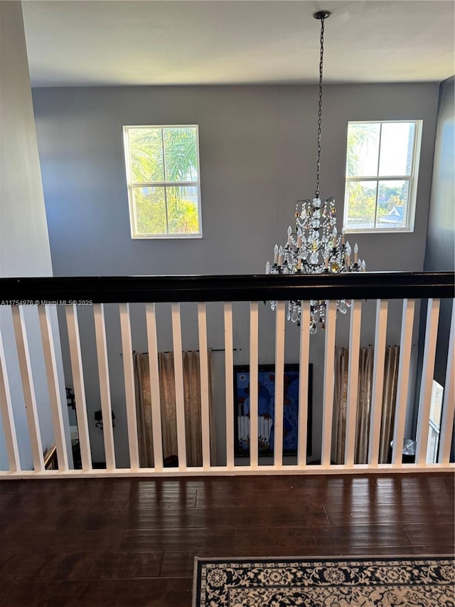 stairs featuring wood finished floors, a wealth of natural light, and an inviting chandelier