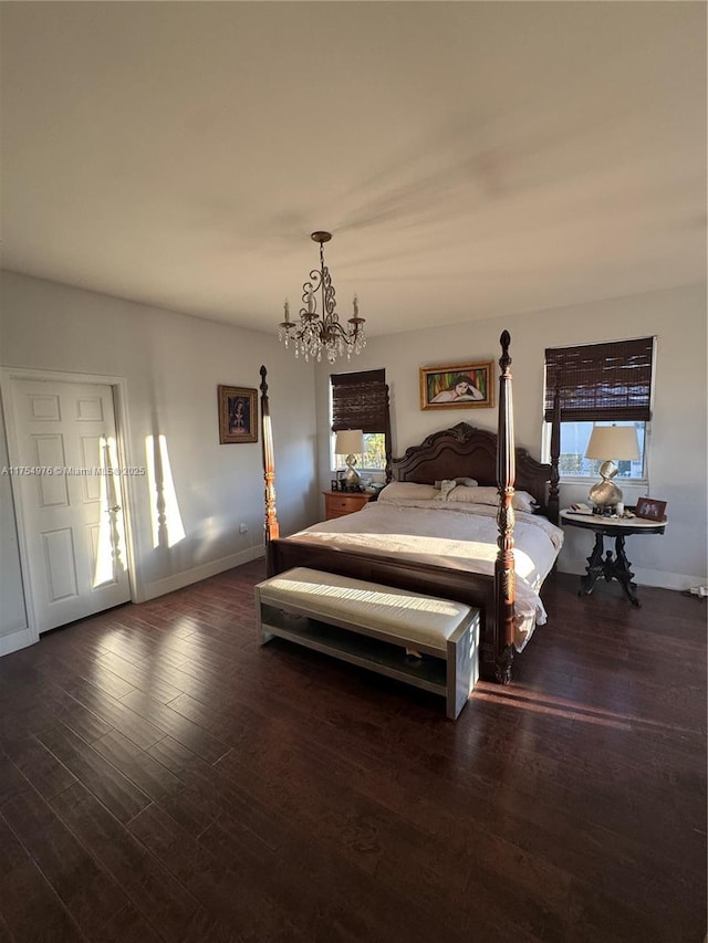 bedroom with baseboards, dark wood-style flooring, and an inviting chandelier