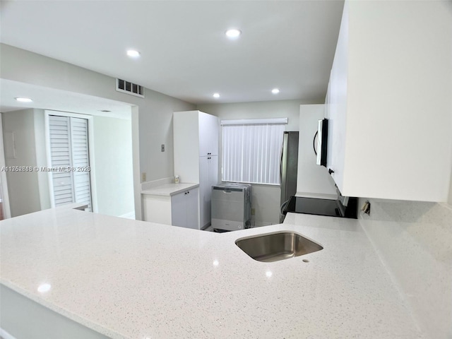 kitchen with light stone counters, visible vents, white cabinetry, electric stove, and fridge