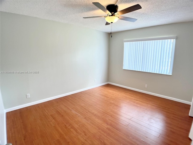 spare room featuring a ceiling fan, a textured ceiling, baseboards, and wood finished floors