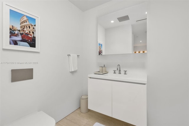 bathroom featuring visible vents, vanity, toilet, and wood finished floors