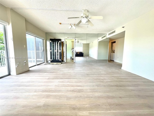 unfurnished room with a textured ceiling, light wood finished floors, visible vents, and a ceiling fan