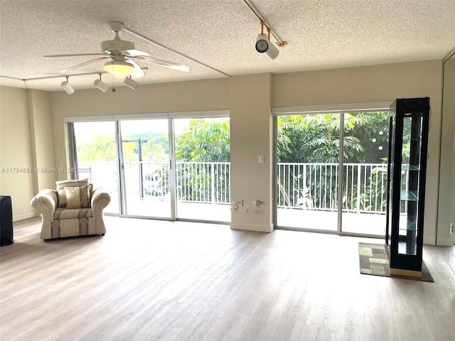 unfurnished living room with ceiling fan, a textured ceiling, and wood finished floors