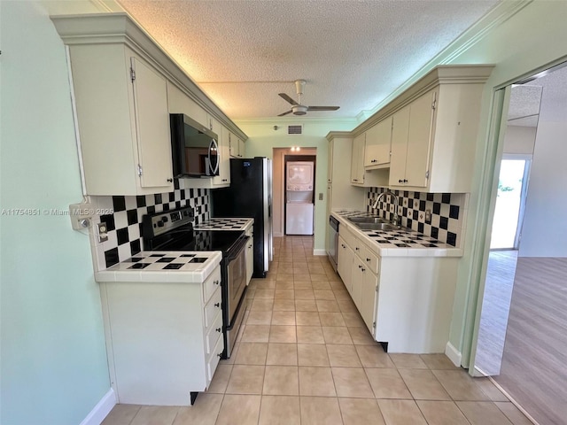 kitchen with tile countertops, stainless steel appliances, light tile patterned flooring, and a sink