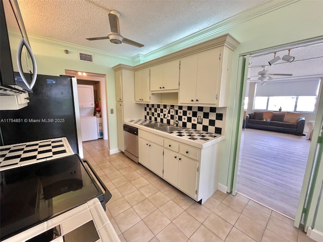 kitchen with tile countertops, a sink, a ceiling fan, appliances with stainless steel finishes, and stacked washing maching and dryer