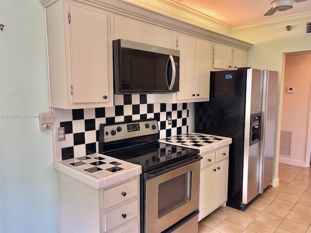 kitchen featuring tile countertops, visible vents, appliances with stainless steel finishes, ornamental molding, and decorative backsplash