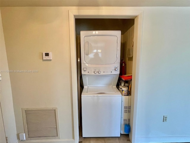 laundry area featuring light tile patterned floors, laundry area, visible vents, and stacked washer / drying machine