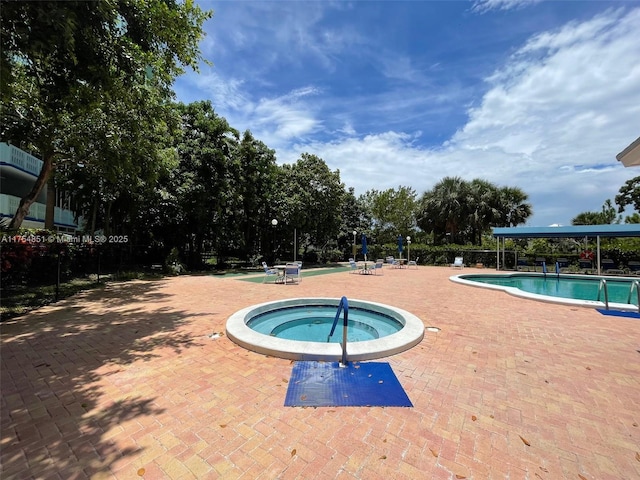 pool with a patio area and a hot tub