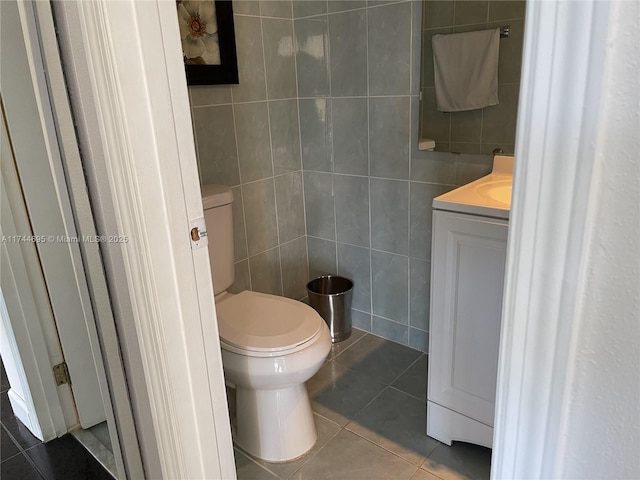 bathroom featuring toilet, tile patterned flooring, tile walls, and vanity