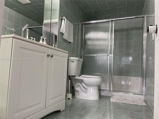 full bath with a stall shower, tile patterned flooring, tile walls, and toilet