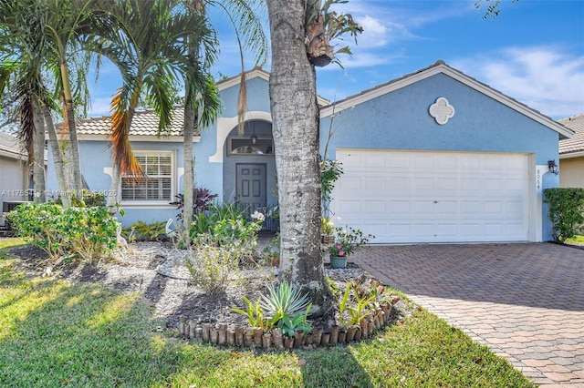 view of front of property featuring a garage, a tiled roof, decorative driveway, and stucco siding