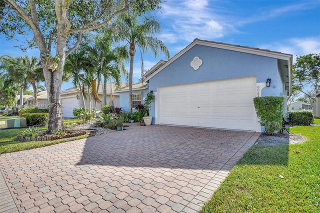 view of front of home featuring decorative driveway, an attached garage, and stucco siding