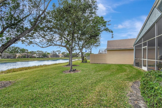 view of yard featuring a sunroom and a water view