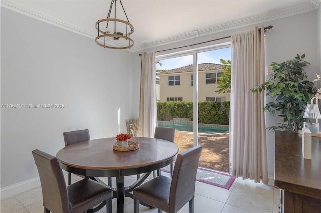 dining space with a notable chandelier, ornamental molding, light tile patterned flooring, and baseboards