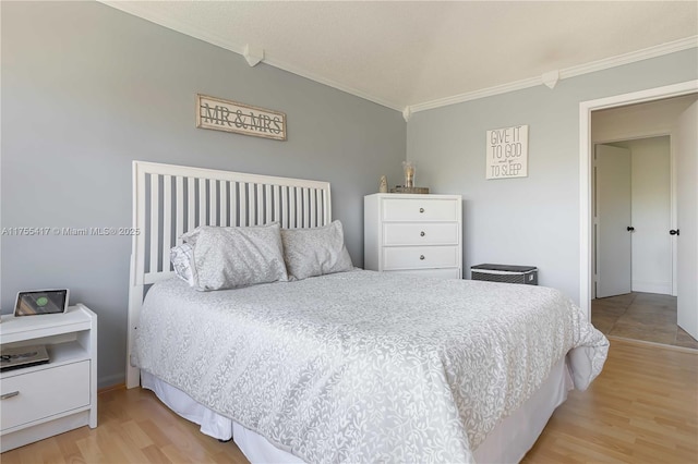 bedroom with ornamental molding and light wood-type flooring