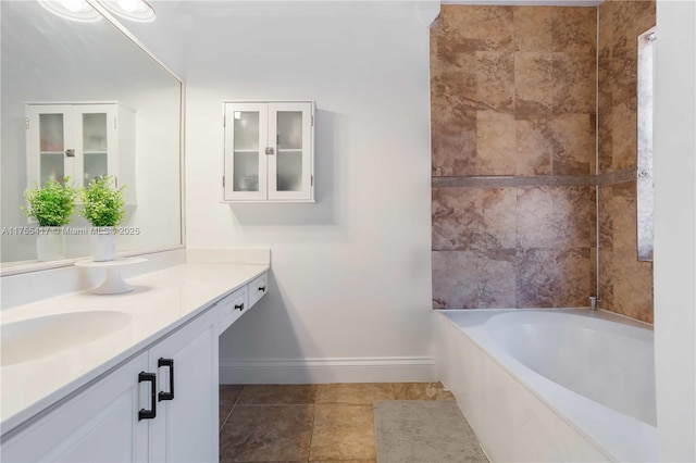 bathroom with tile patterned floors, a bathtub, vanity, and baseboards