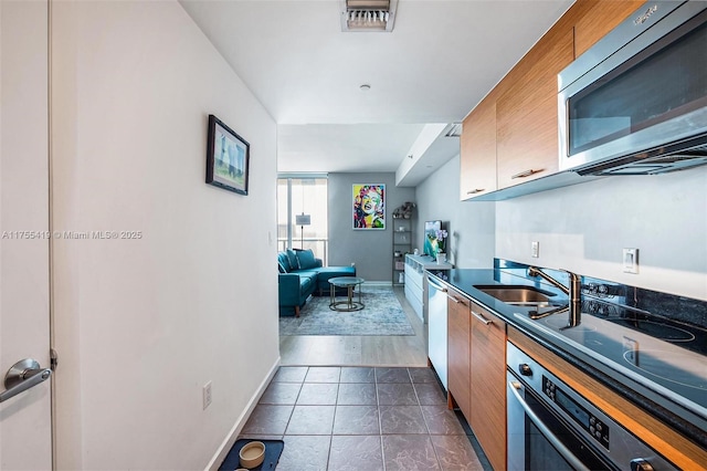 kitchen featuring dark tile patterned floors, a sink, visible vents, baseboards, and appliances with stainless steel finishes