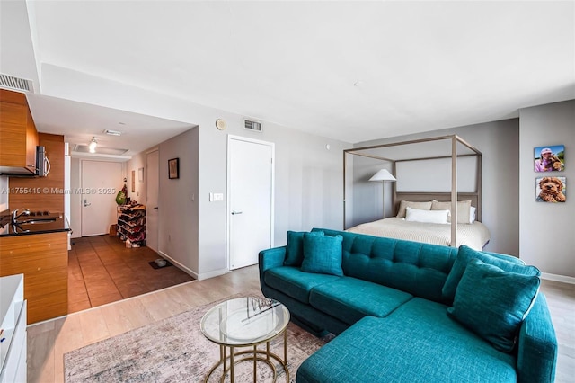 living room featuring light wood-style flooring, visible vents, and baseboards