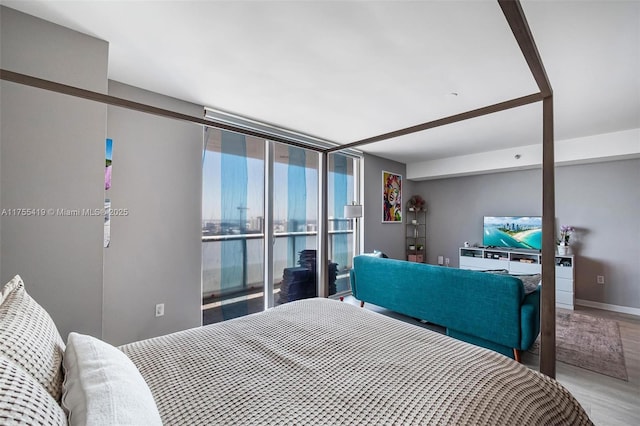 bedroom featuring a wall of windows, baseboards, and wood finished floors