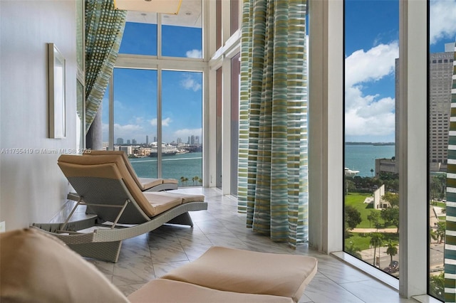 living area featuring a water view, marble finish floor, a view of city, and a wealth of natural light