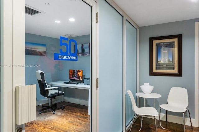 office area with baseboards, visible vents, radiator heating unit, and wood finished floors