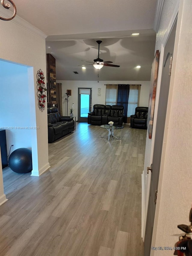 unfurnished living room with light wood-style floors, ornamental molding, baseboards, and a ceiling fan