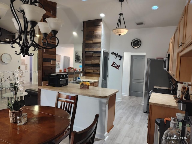 kitchen with visible vents, appliances with stainless steel finishes, a sink, light countertops, and hanging light fixtures