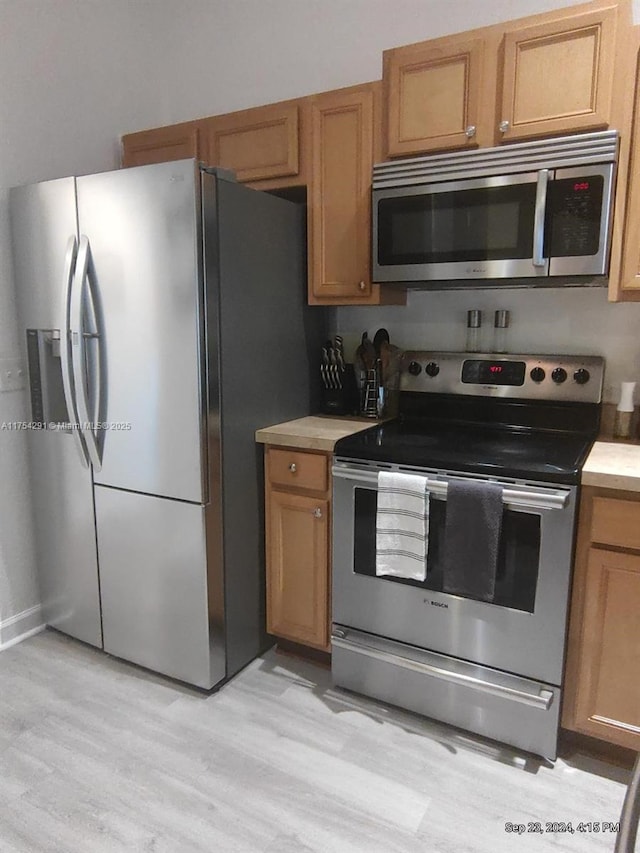 kitchen featuring brown cabinets, light countertops, light wood finished floors, and stainless steel appliances