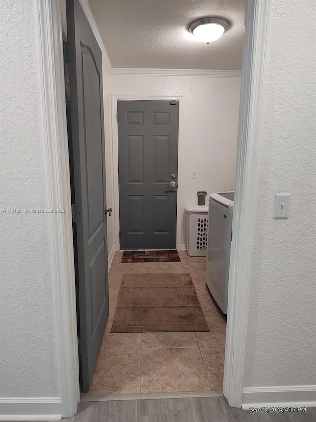 interior space featuring washer / clothes dryer, a textured ceiling, a textured wall, and ornamental molding