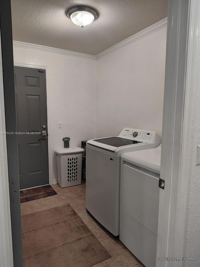 clothes washing area featuring crown molding, washer and clothes dryer, laundry area, and a textured ceiling