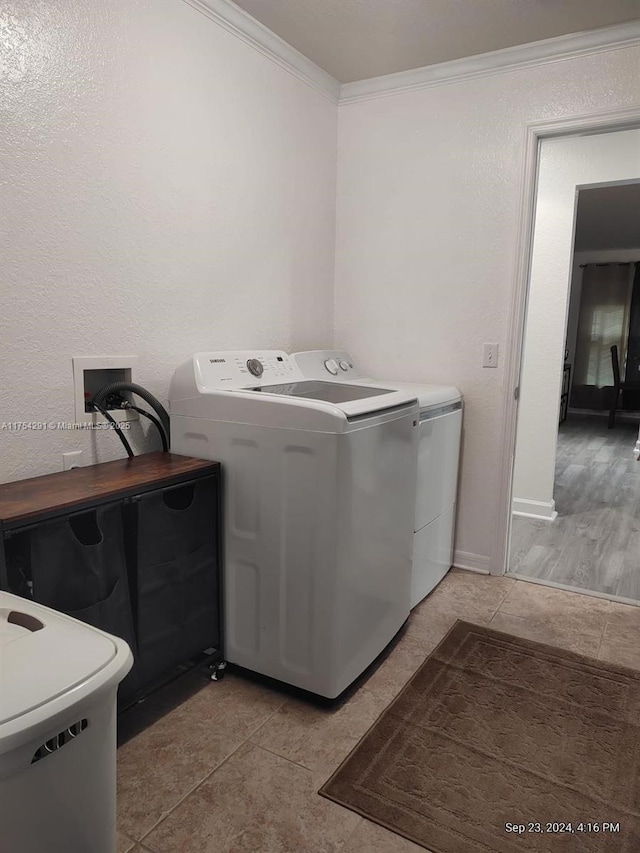 washroom with crown molding, washing machine and dryer, light tile patterned flooring, and laundry area
