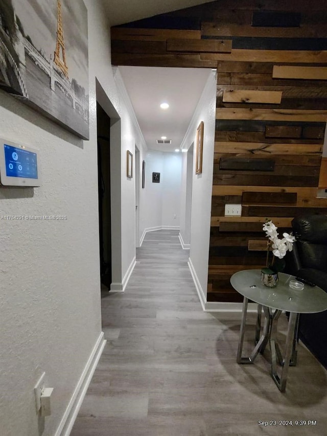 hallway featuring crown molding, wood finished floors, baseboards, and vaulted ceiling
